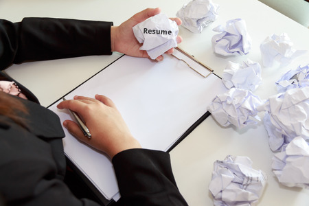 hands of female crumple sheets of resume at the desk mistake
