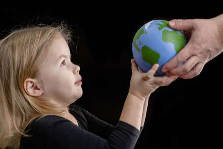 La mère donne la planète entre les mains d'un enfant. isolé sur fond sombre.