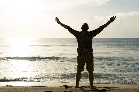 silhouette of a man with outstretched arms and facing the sun