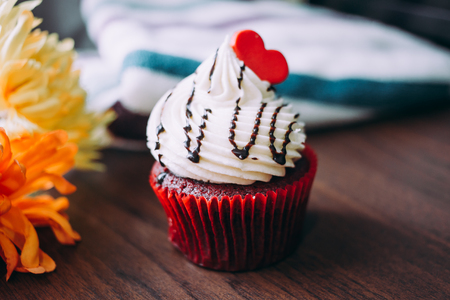 Red cupcakes with cream on top and heart shaped sugar placed on the table near the window in the morning vintage tone Stock Photo