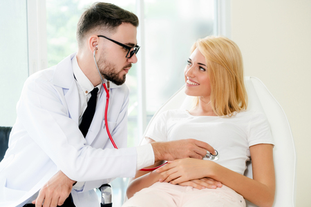 Male doctor is talking and examining female patient in hospital office. Healthcare and medical service. Stock Photo