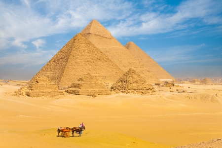 The Giza pyramids lined up in a row against a beautiful blue sky in Cairo, Egypt Фото со стока