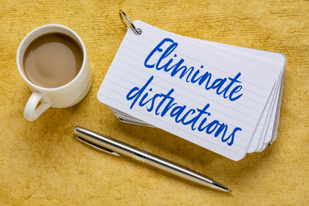 Eliminate distractions - handwriting on a stack of index cards with a cup of coffee and  a pen against yellow textured paper