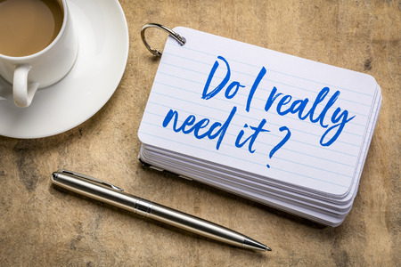 Do I really need it? Minimalism concept - handwriting on a stack of index cards with a cup of coffee and  a pen.