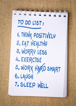 inspiring and positive to do list  - handwriting in a spiral sketchbook against burlap canvas background