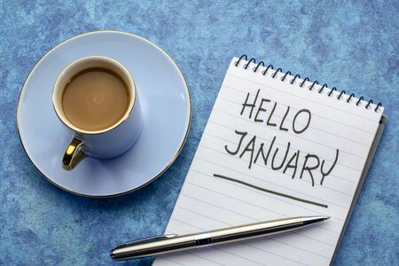 Hello January - handwriting in a notebook with a cup of coffee
