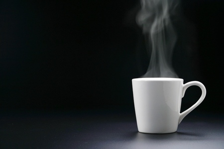 Hot white coffee cup or tea and steam vapor on black desk table and black background.copy space blank for text.empty for word