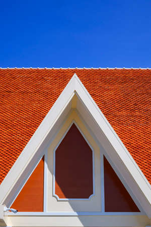 Gable roof with clay roof tiles on top of thai traditional pavilion against blue sky background in vertical frame