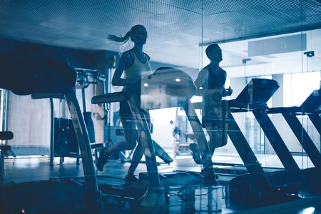 Active young people running on treadmills in sports club