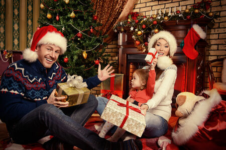 happy family celebrating christmas at home by the fireplace and the christmas tree stock photo - Celebrating Christmas happy family celebrating christmas at home by the fireplace and the christmas tree stock photo - Celebrating Christmas