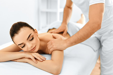 Massage: Spa Женщина. Лечение красоты. Красивая молодая здоровая девушка Кавказа, расслабляющий с процедуры Ручной массаж в спа-салоне. Массажист, втирание ее обратно. Уход за телом. Уход за кожей, здоровье, благополучие. Фото со стока