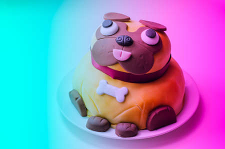 Pug dog cake, sponge with a frosting and raspberry jam filling, covered and decorated with soft icing and edible decorations, birthday cake
