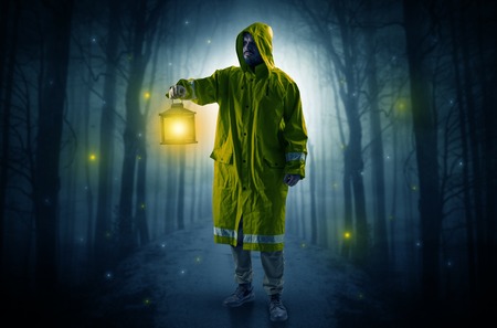 Mysterious man coming from a path in the forest with glowing lantern concept Stock Photo