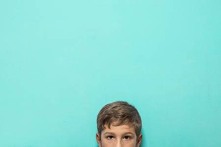 Portrait of a blond child on a blue background, with space for text