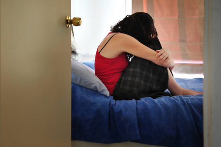 sad lonely: Depressed young woman sitting on the bed at home suffering from a severe depression