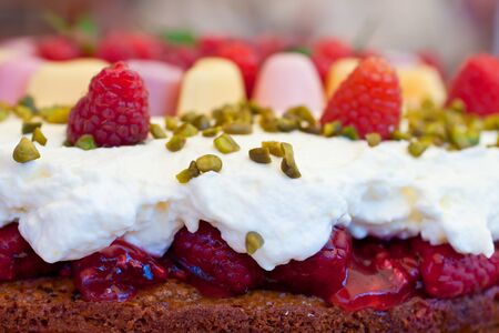 Seitenansicht einer himbeertorte mit sahne, pistazien und weingummi Stock Photo