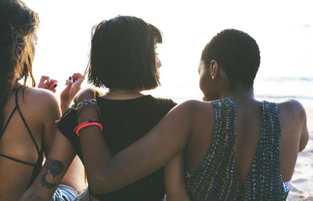 A diverse group of woman friends sitting at the beach together Reklamní fotografie