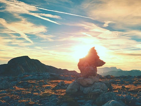 Sharp stones stacked at trail run heavy pebbles stack on dry grass on mountain at trekking path evening orange sky background