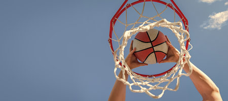 Basketball player throws the ball into the hoop on sky background targeting horizontal poster design web banner header copy space