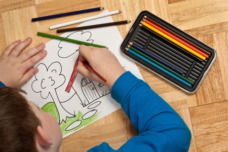 Young Boy In Blue Shirt Coloring A Picture With Pencils While ... Young Boy In Blue Shirt Coloring A Picture With Pencils While ...