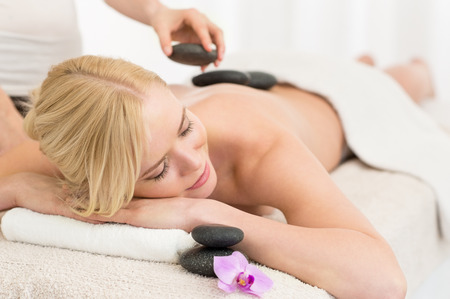 Massage: Красивая молодая женщина, получающих массаж горячими камнями в салоне спа