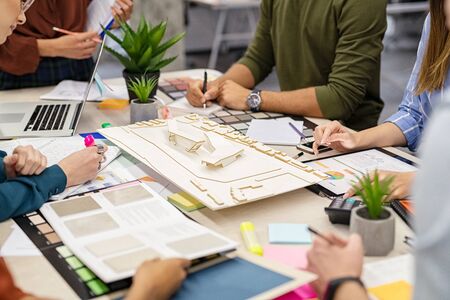 Team Of Architects And Engineers Working On Urban Building Model Scale. Hand Of Colleagues In Architectural Studio Working Together On A House Project. Close Up Of People Hand Working Together Around Prototype Of A Shopping Center Site.