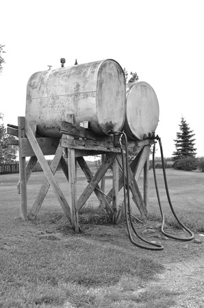 old fuel tanks on a farm with hoses which lay on the ground black and white