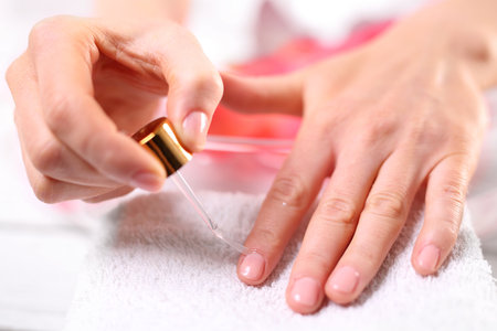 Woman paints the nails cuticle oil and nail Фото со стока