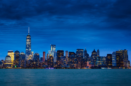 New york city manhattan downtown skyline at night with illuminated skyscrapers and cloudy sky