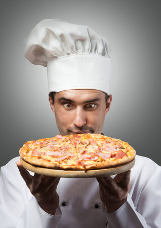 Humorous portrait of a man in chef s hat smelling pizza