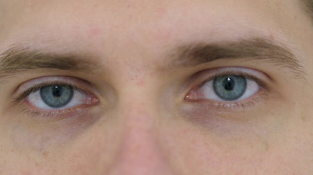 blinking eyes of young man close up at work in office stock photo