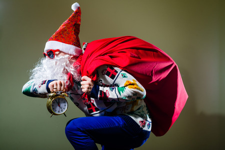 Picture of funny santa claus with alarm clock wearing heart shape sunglasses on bright festive bokeh background