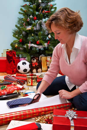 photo of a woman sat on a rug at home wrapping her christmas presents christmas - Generic Christmas Gifts photo of a woman sat on a rug at home wrapping her christmas presents christmas - Generic Christmas Gifts