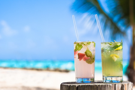 coconut: hai ly cocktail mohito ướp lạnh và kính mát trên bàn gần bãi biển