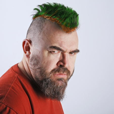 Close up portrait profile of a white man with mohawk and beard screams in a angry state