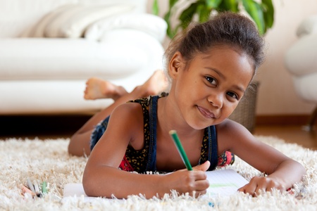 African children: Little African Asian girl  drawing, lying down on the floor