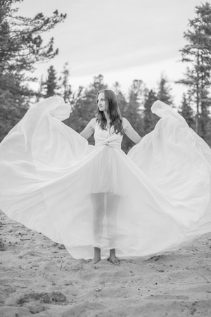 美しい少女は ビーチで風になびく彼女のドレスのダンスします の写真素材 画像素材 Image