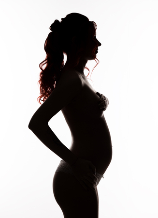 silhouette of beautiful woman on a early gestation, pregnant belly