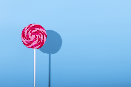 Pink lolipop candy with shadow on pastel blue background minimal style concept new minimalism punchy pastels