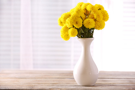 Beautiful flowers in vase with light from window Фото со стока
