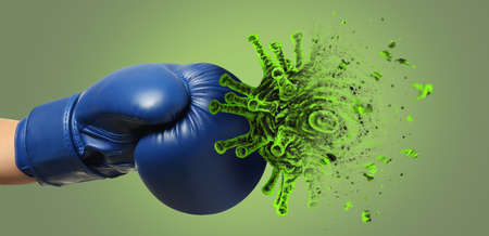 Hand in boxing glove kicking cigarette on green background. concept of immunity