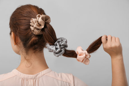 Woman with silk scrunchies on ponytail against gray background