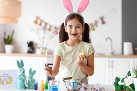 Petite fille drôle peignant des oeufs de pâques à la maison