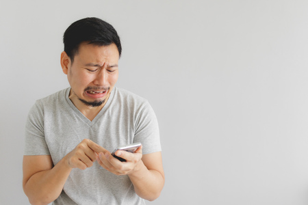 Asian man cry and sad with what show on the smartphone.
