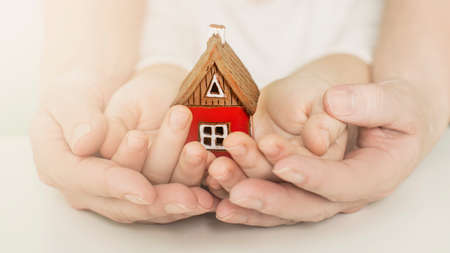 Immobilier et concept de maison familiale - photo en gros plan de mains d'enfants et de femmes tenant une maison en papier rouge avec la famille. photo de haute qualité Banque d'images