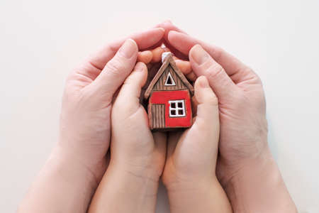 Immobilier et concept de maison familiale - photo en gros plan de mains d'enfants et de femmes tenant une maison en papier rouge avec la famille. photo de haute qualité Banque d'images