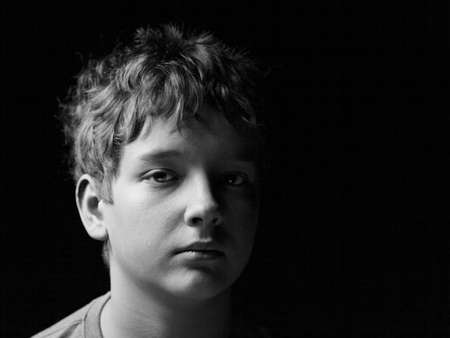 sad lonely: Portrait sad teenage boy on a black background