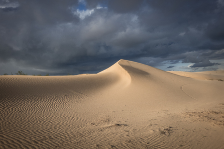 Sun and dark dramatic cloads creating a beautiful interesting sky over desert sands in the natural park in corralejo, fuerteventura, las palmas, canary islands, spain