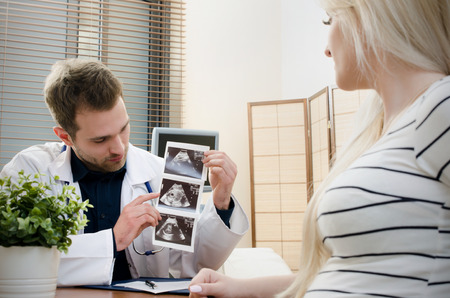 Doctor showing baby ultrasound image to pregnant woman. showing ultrasound usg pregnancy gynecologist patient pregnant concept Stock Photo