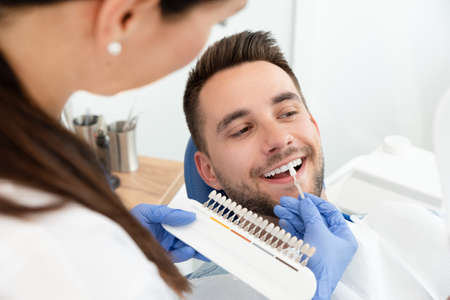Przystojny młody mężczyzna w klinice stomatologicznej z kobietą dentystą. zdrowe wybielanie zębów.